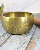 Brass singing bowl with engraved symbols on a wooden surface