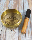 Brass singing bowl with wooden striker on a wooden surface