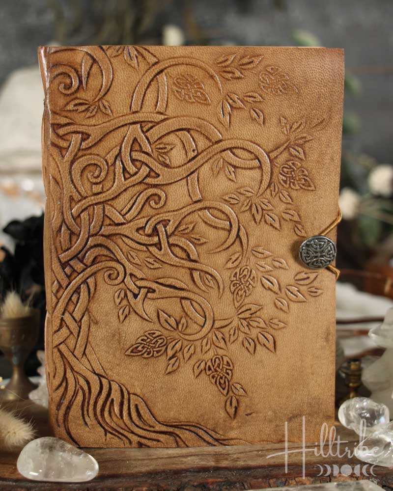 Brown leather journal with embossed designs and a metal clasp on a wooden surface.
