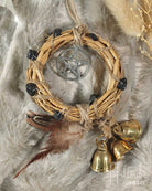 Woven wreath with pentacle pendant, feathers, and gold bells on a fur background